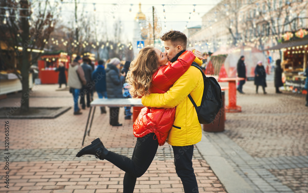 romantic couple in love kissing, hugging, walking on the street, wearning in bright down jackets. urban background.