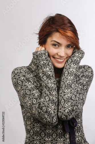 Bella ragazza con i capelli a caschetto si scalda grazie al suo maglione fantasia e si tiene il viso  isolata su sfondo photo