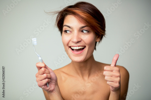 bella ragazza con i capelli corti è felice di lavarsi i denti, isolata su sfondo chiaro photo