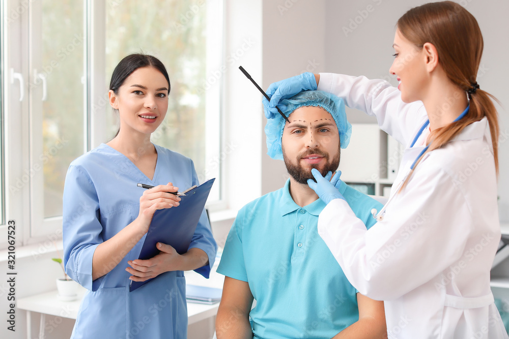 Obraz premium Plastic surgeon applying marks on patient's face in clinic