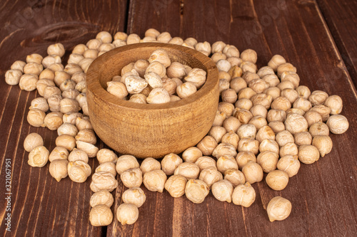 Lot of whole fresh tan chickpea in bamboo bowl on brown wood