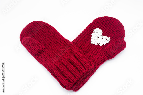 A knitted red mittens with white snowflakes in the shape of a heart on a white background  isolated. Concept of Christmas  winter  love. Care and Valentine s day. Copy space