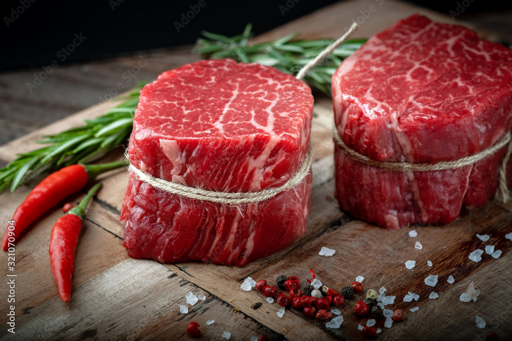 Raw beef filet Mignon steak on a wooden Board with pepper and salt, black Angus marbled meat Raw beef filet Mignon steak on a wooden Board with pepper and salt, black Angus marbled meat