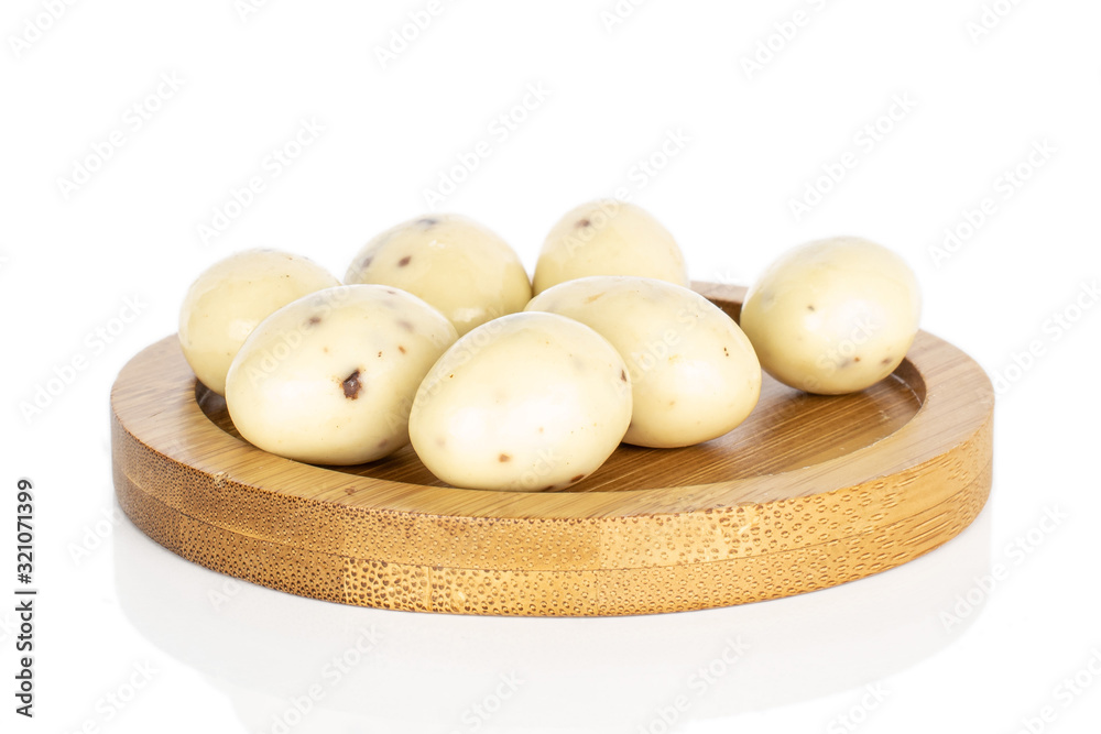 Lot of whole coated white almond nut stracciatella on round bamboo coaster isolated on white background Lot of whole coated white almond nut stracciatella on round bamboo coaster isolated on white background