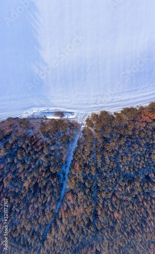 Aerial winter landscape. Snow covered forest and field