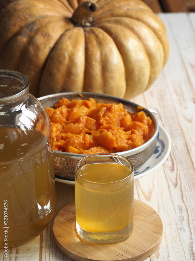 The use of pumpkin and pumpkin juice. Use in medicine. Juice in a glass glass on a wooden background. The use of pumpkin and pumpkin juice. Use in medicine. Juice in a glass glass on a wooden background.