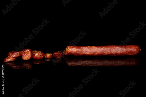 One half lot of slices of piquant smoked sausage isolated on black glass