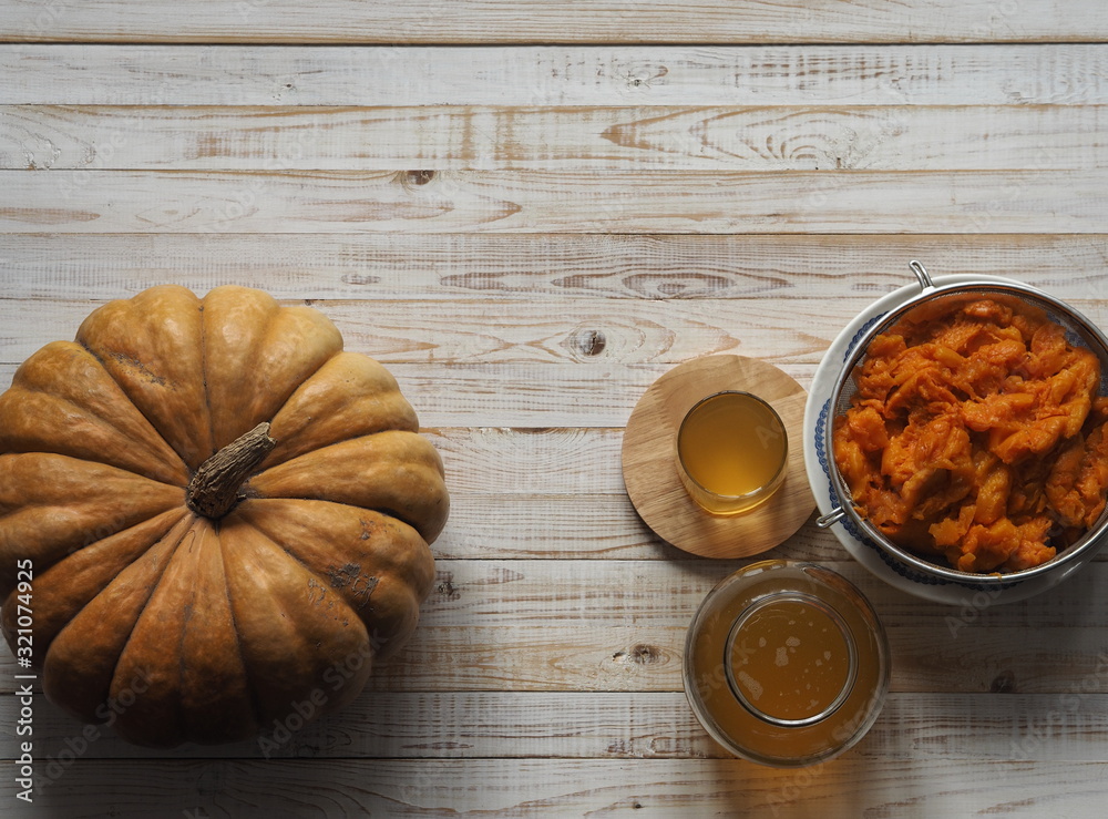 The use of pumpkin and pumpkin juice. Use in medicine. Juice in a glass glass on a wooden background. The use of pumpkin and pumpkin juice. Use in medicine. Juice in a glass glass on a wooden background.