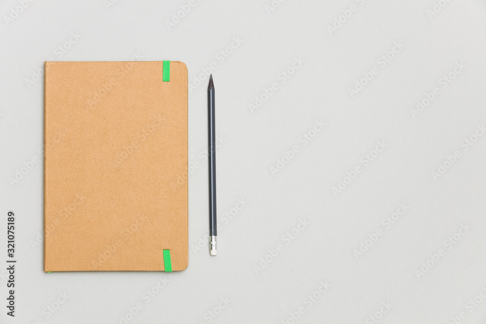 Top view of closed craft cover notebook with pencil on gray desk background Top view of closed craft cover notebook with pencil on gray desk background