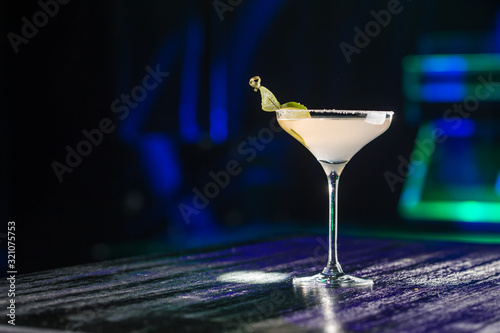 Margarita cocktail with lime slice on bar table on night club background