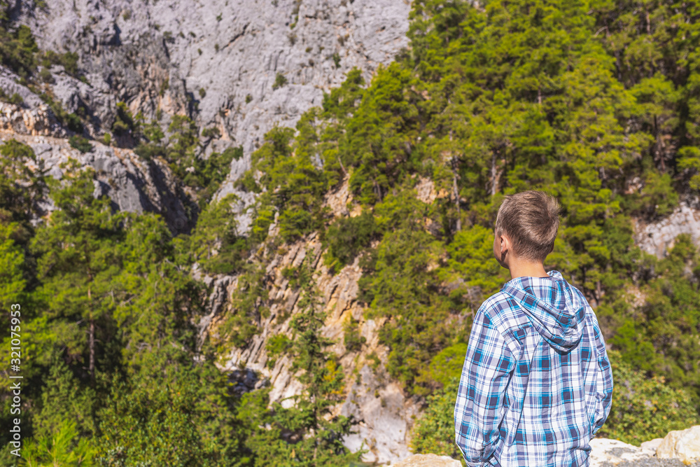 Young white kid standing in scenic landscape of canyong looking at beautiful high mountains. Travel and hiking concept. Young white kid standing in scenic landscape of canyong looking at beautiful high mountains. Travel and hiking concept.