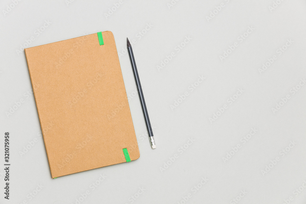 Top view of closed craft cover notebook with pencil on gray desk background Top view of closed craft cover notebook with pencil on gray desk background