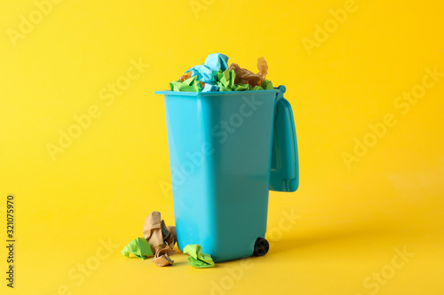 Canvastavla Recycle bin with trash on yellow background, space for text