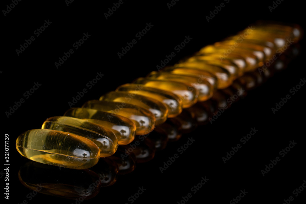 Lot of whole golden fish oil diagonal isolated on black glass Lot of whole golden fish oil diagonal isolated on black glass