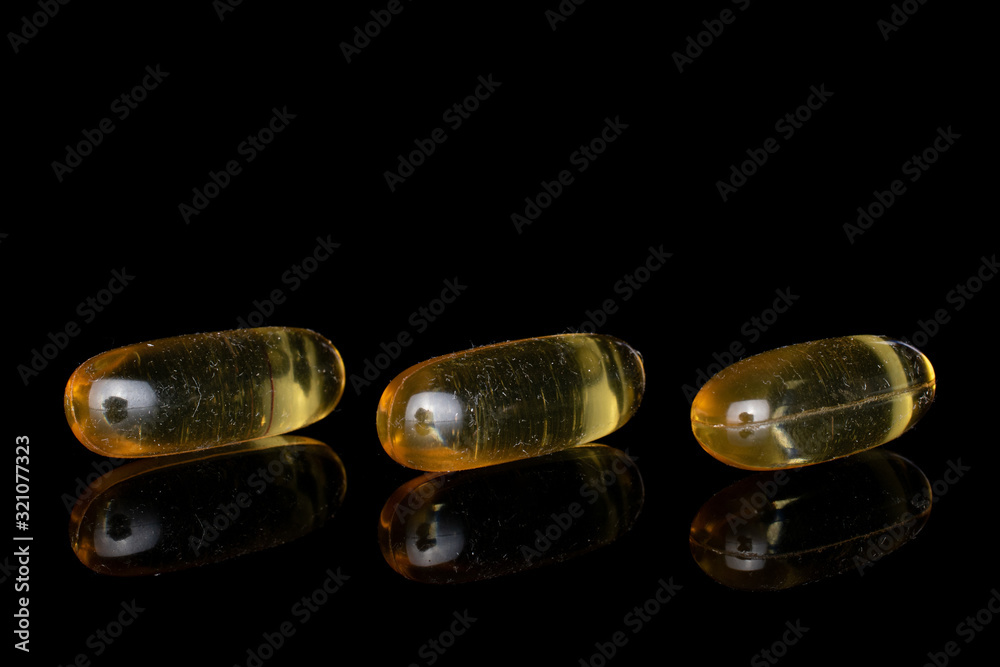 Group of three whole golden fish oil isolated on black glass Group of three whole golden fish oil isolated on black glass