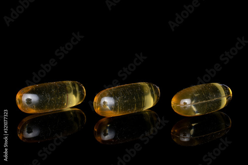 Canvas Print Group of three whole golden fish oil isolated on black glass