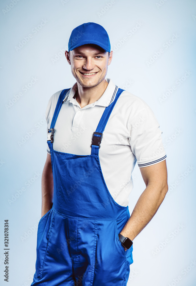 Portrait of young worker man wearing blue uniform. Isolated on grey background with copy space. Human face expression, emotion. Business concept. Portrait of young worker man wearing blue uniform. Isolated on grey background with copy space. Human face expression, emotion. Business concept.