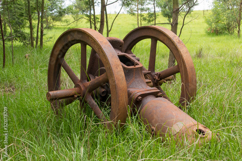 Old fashioned wheel operated water pump, abandoned in the grass, rusted and brown in the Drakensberg, South Africa