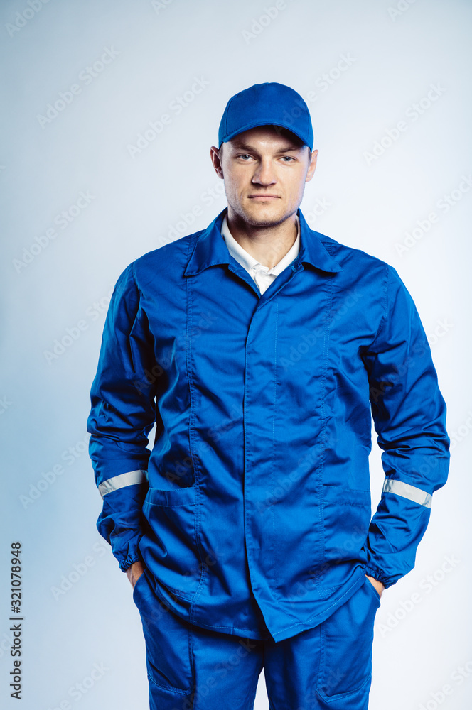 Portrait of young worker man wearing blue uniform. Isolated on grey background with copy space. Human face expression, emotion. Business concept.