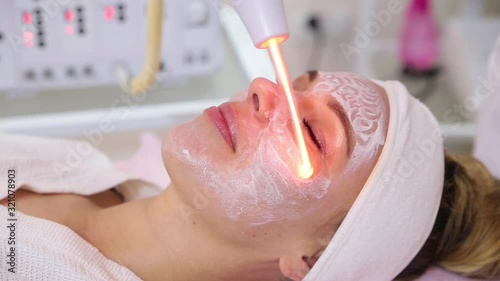 Receiving electric darsonval facial massage procedure.