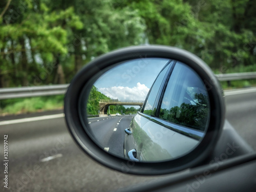 Motorway and traffic reflected in rear view wing mirror on car
