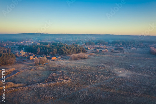 The surroundings of the Ukrainian village in the autumn clear weather. Aerial photo of village houses near the forest in a blue haze on the horizon.