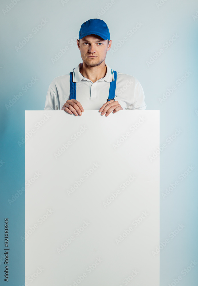 Mockup image of a young pensive worker holding empty white banner. White or blue background. Bussines concept. Mockup image of a young pensive worker holding empty white banner. White or blue background. Bussines concept.
