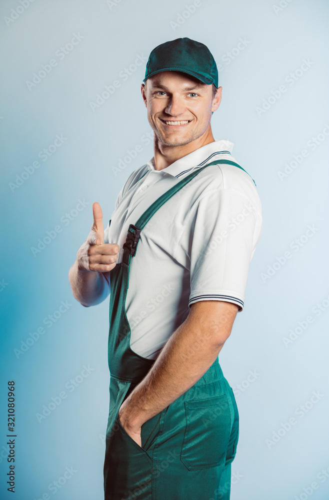 Portrait of young worker man wearing green uniform. Pointing finger at you looking at camera. Isolated on grey background with copy space. Human face expression, emotion. Business concept. Portrait of young worker man wearing green uniform. Pointing finger at you looking at camera. Isolated on grey background with copy space. Human face expression, emotion. Business concept.