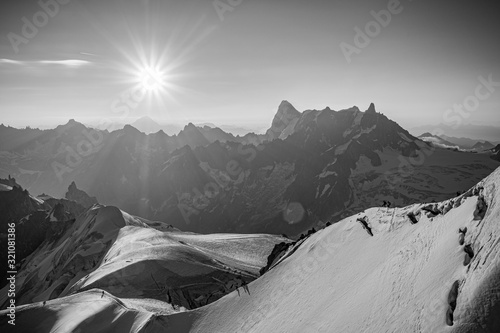 A black and white photo of the sun rising over Mont Blanc
