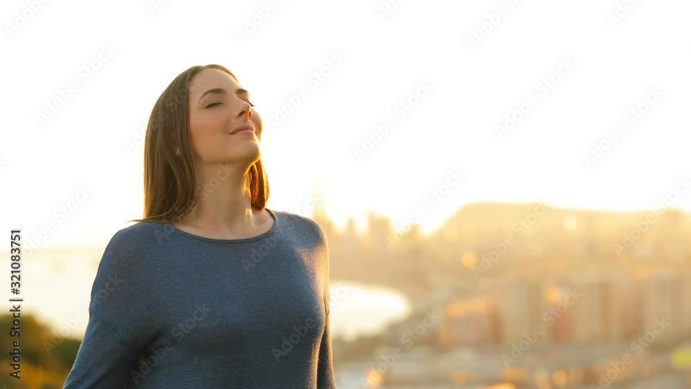 Woman relaxing breathing deeply fresh air in city outskirts at sunset