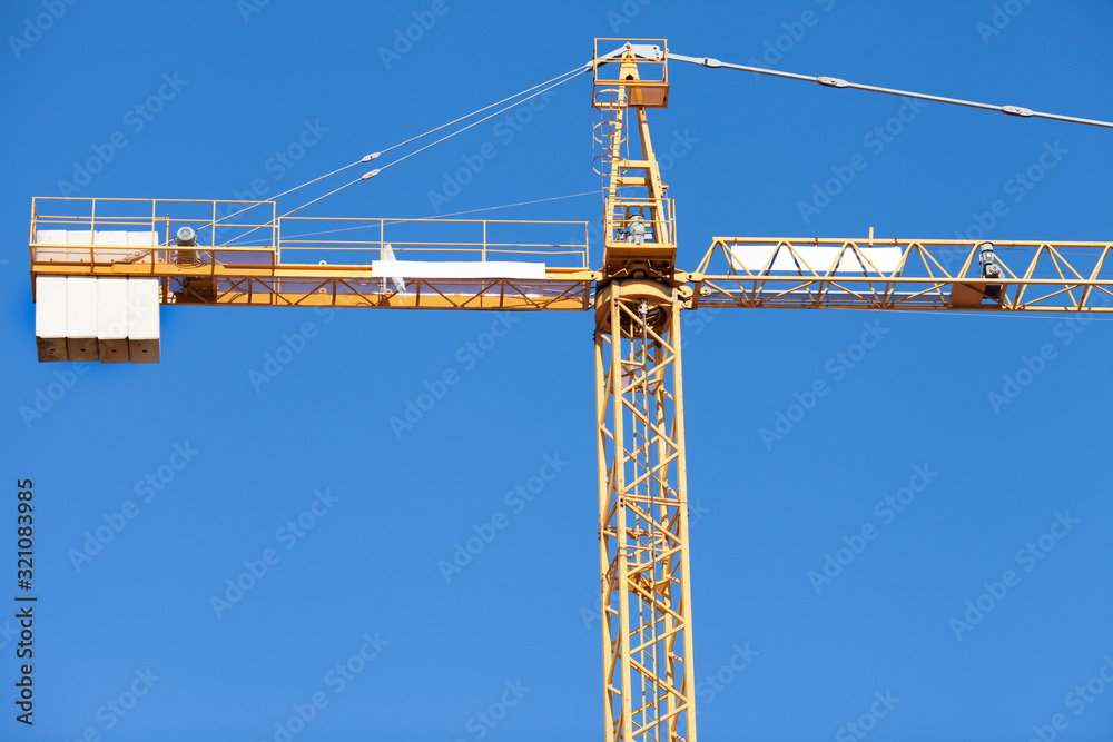 Yellow construction crane on a background of blue sky. Space for a text. Yellow construction crane on a background of blue sky. Space for a text.