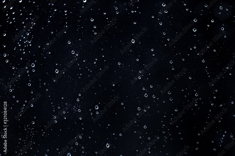 Fototapeta premium Rain water drops on a black dramatic window glass. Autumn depression background. Rain pattern.