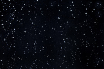 Rain water drops on a black dramatic window glass. Autumn  depression background. Rain pattern.