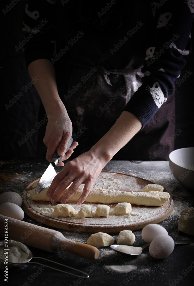 Concept of Russian cuisine. Lazy dumplings on a dark background with hands. Cooking process