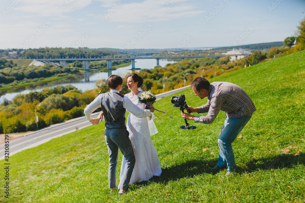 Wedding photographer taking pictures of the bride and groom on a hillside Wedding photographer taking pictures of the bride and groom on a hillside