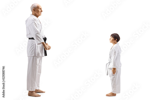 Karate boy standing and looking at his mature karate instructor