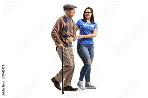 Young female volunteer helping an elderly man with a walking cane