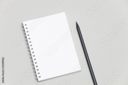 Blank notebook or notepad with pencil on gray desk background
