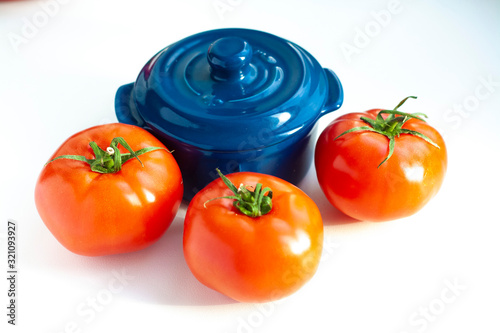 Vegetables tomatoes, blue pot on a white background