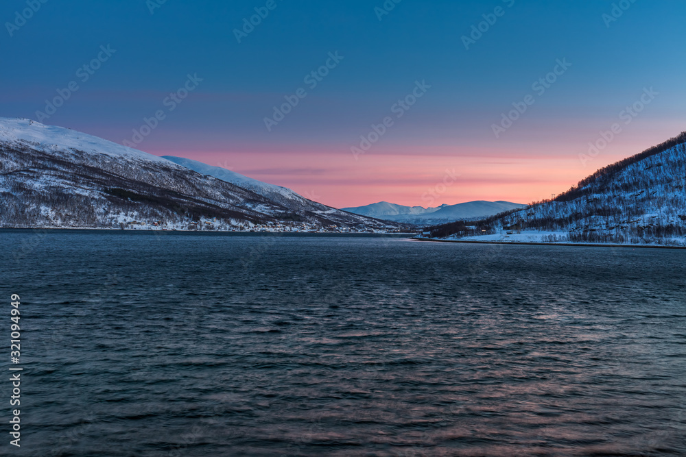 Amazing sunset with amazing magenta color over fjord Tromso, Norway. Polar night. long shutter speed