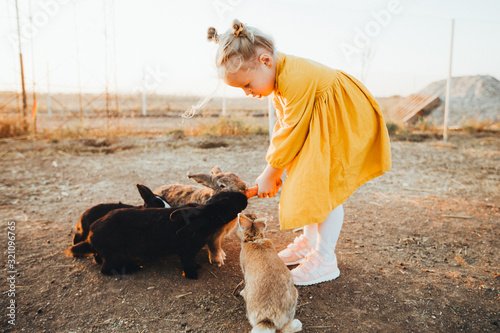 Little girl playing with the rabbits in the petting zoo. Easter tradition of visiting a rabbit.