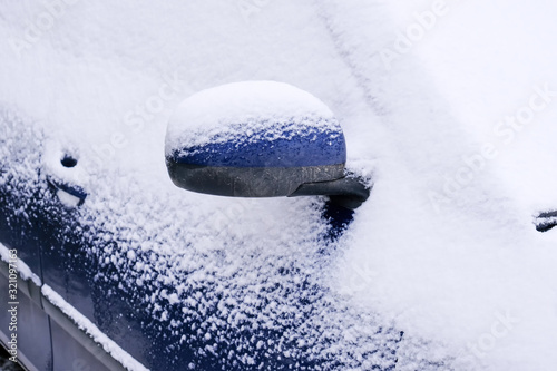 Snow covered car in an open parking