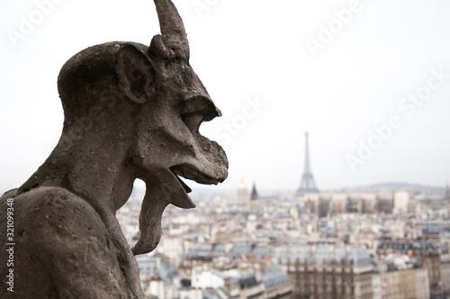 Close up of the Gargoyle on Notre Dame Cathedral, Paris, France, with blured Eiffel Tower in background.