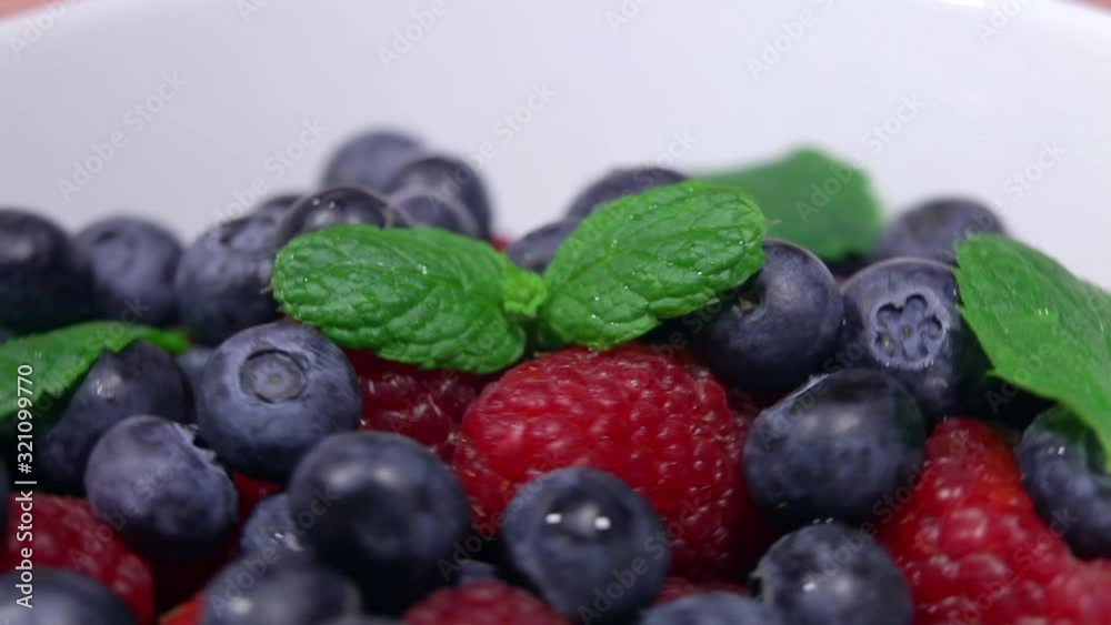 Blueberries and raspberries in a plate with mint petals, forgiveness in a circle. Blueberries and raspberries in a plate with mint petals, forgiveness in a circle.