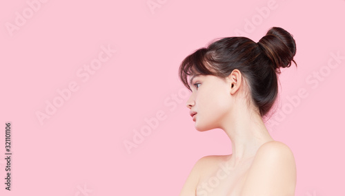 Beautiful young asian korean woman with clean fresh skin touching her own face. Face treatment. Cosmetology, beauty and spa. Pink background photo