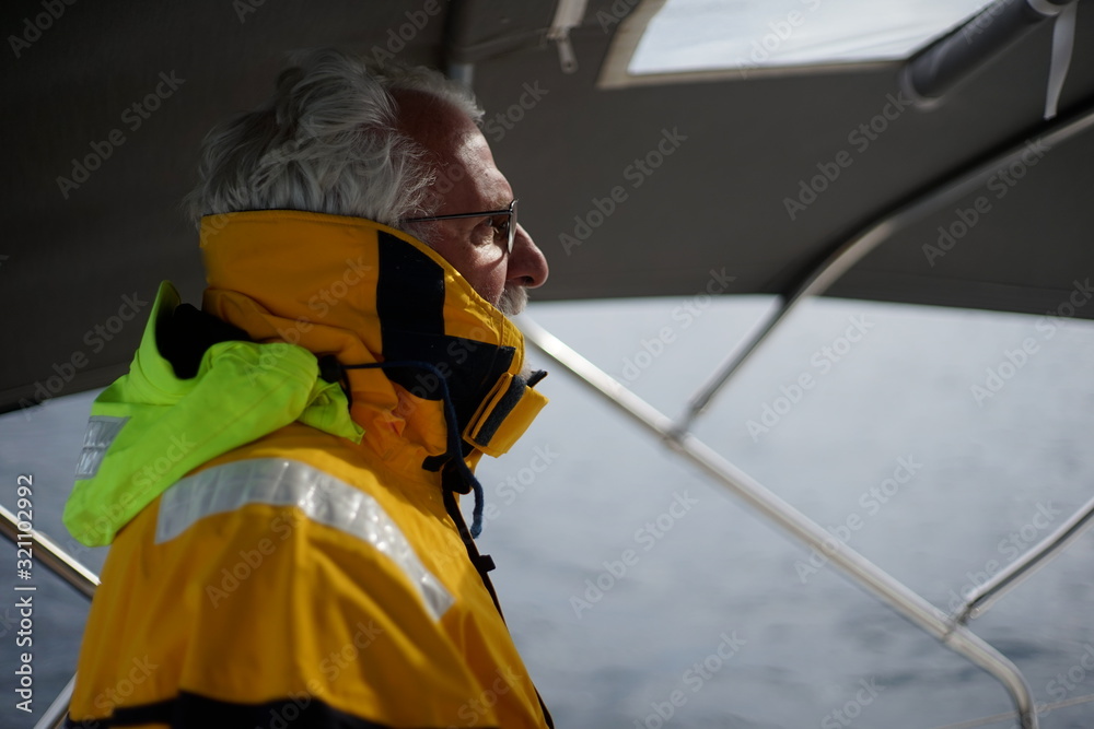 Fototapeta White bearded sailing senior, experienced skipper on a sailboat