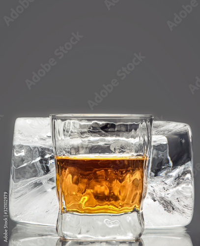 Glass with an alcoholic drink on the background of a large block of rectangular ice photo