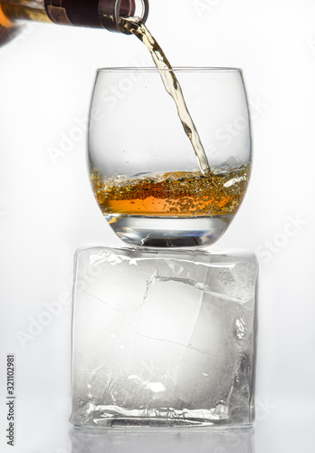 Glass with an alcoholic drink on a large piece of ice
