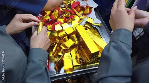 A group of women preparing fake gold bars for offering to ancesters in Chinese New Year festival.