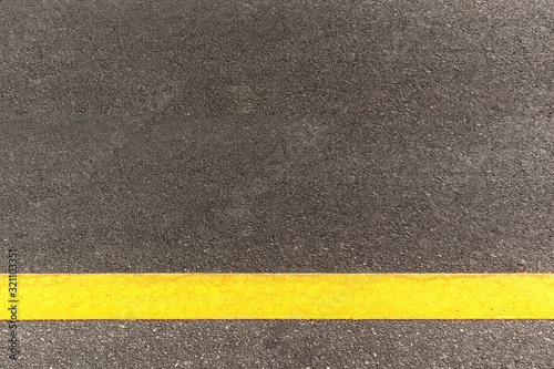 Black asphalt road texture with marking background. Horizontal yellow line on asphalt road. © lllonajalll